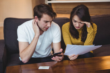 A couple with worried faces discussing a financial document