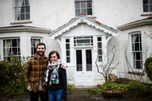 A happy couple standing near the house